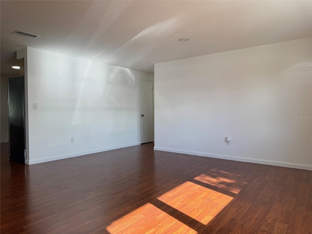 spare room with a textured ceiling and dark hardwood / wood-style flooring