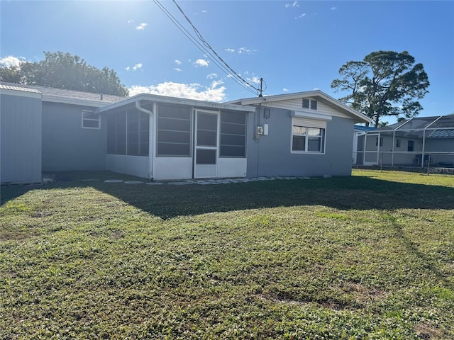 back of property featuring a sunroom and a lawn