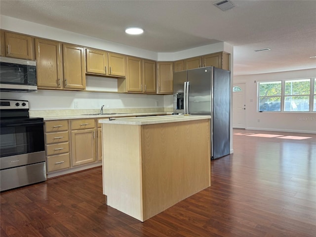 kitchen featuring sink, dark wood-type flooring, a center island, and appliances with stainless steel finishes