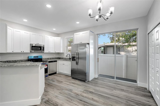 kitchen with white cabinetry, appliances with stainless steel finishes, plenty of natural light, light stone countertops, and sink