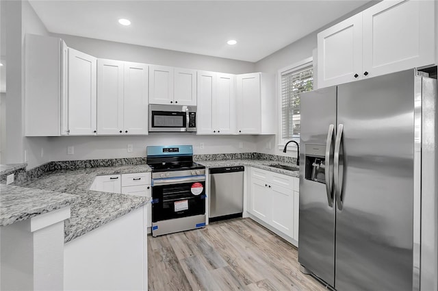 kitchen featuring light stone countertops, appliances with stainless steel finishes, sink, and white cabinetry