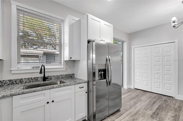 kitchen with white cabinets, sink, light stone countertops, and stainless steel fridge with ice dispenser