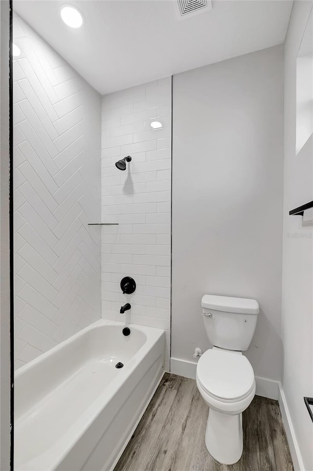 bathroom with toilet, tiled shower / bath, and hardwood / wood-style flooring