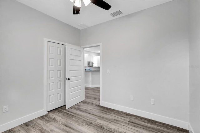 unfurnished bedroom with ceiling fan, a closet, and light hardwood / wood-style flooring