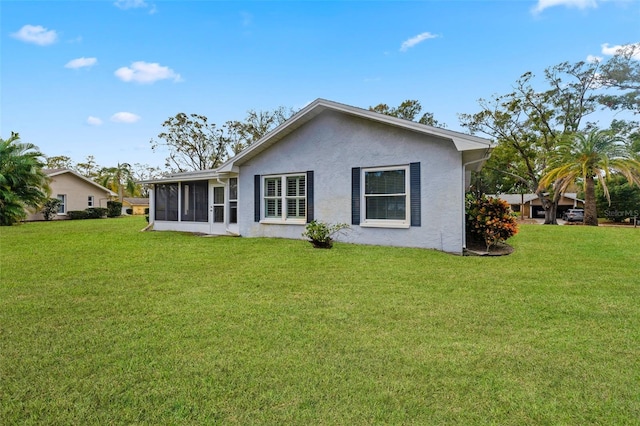 back of house featuring a sunroom and a lawn