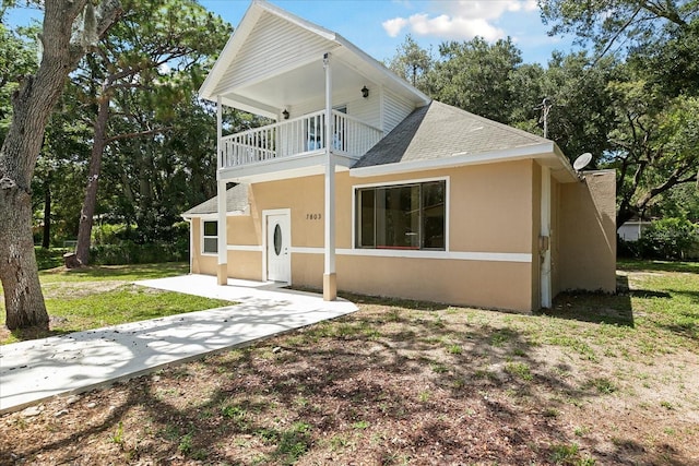 back of property with a balcony and a lawn