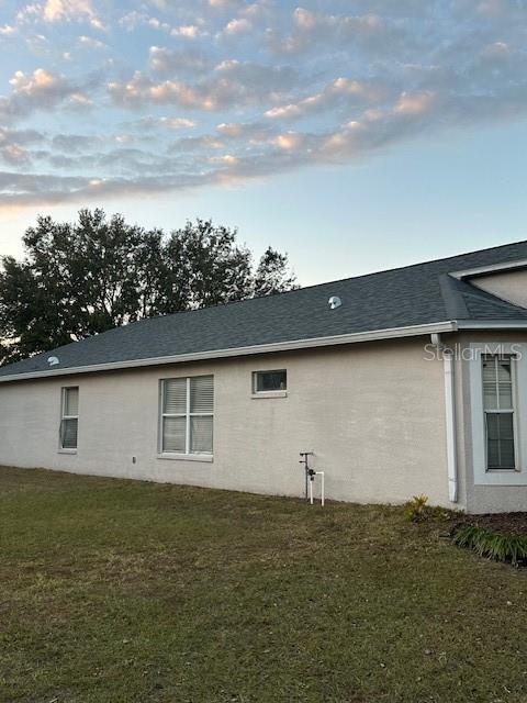 property exterior at dusk featuring a lawn