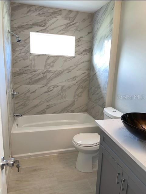 full bathroom featuring toilet, tiled shower / bath combo, tile patterned flooring, and vanity