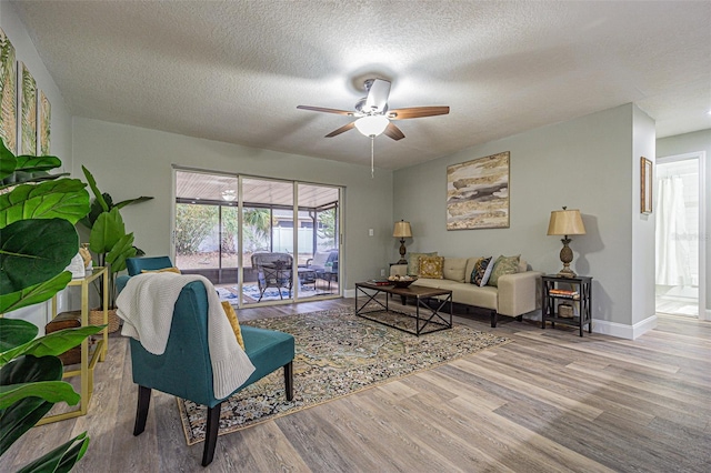 living room with hardwood / wood-style flooring, a textured ceiling, and ceiling fan