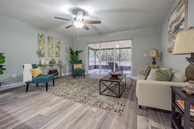 living room with a textured ceiling, ceiling fan, and hardwood / wood-style flooring