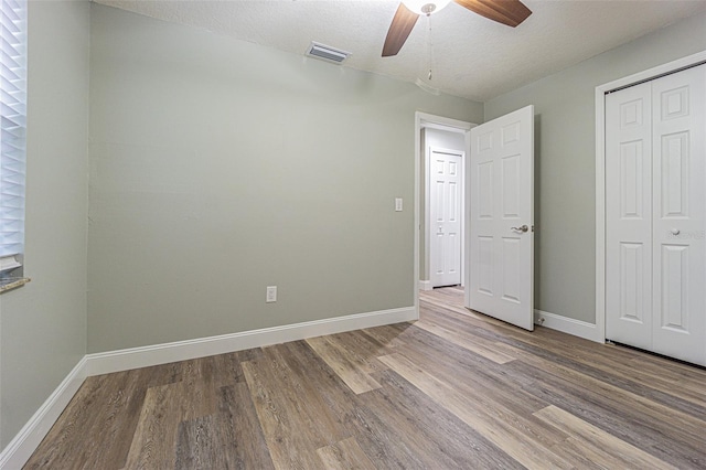 unfurnished bedroom featuring a closet, a textured ceiling, ceiling fan, and light hardwood / wood-style floors