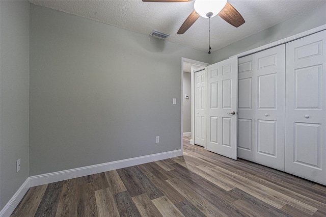 unfurnished bedroom featuring ceiling fan, a closet, a textured ceiling, and wood-type flooring