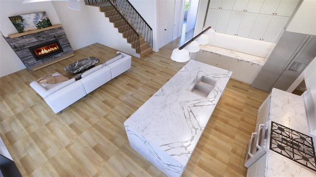 living room with light wood-type flooring, a fireplace, and sink