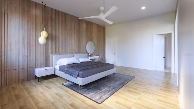 bedroom with light wood-type flooring, ceiling fan, and wood walls