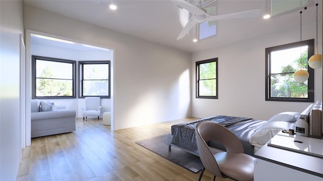 bedroom featuring ceiling fan, multiple windows, and light hardwood / wood-style flooring