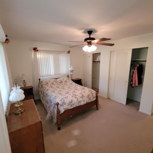 carpeted bedroom featuring ceiling fan and multiple closets