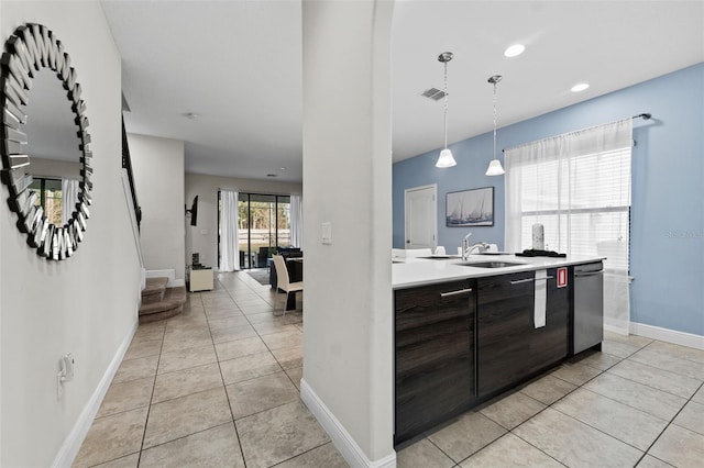 kitchen featuring dishwasher, hanging light fixtures, dark brown cabinetry, sink, and light tile patterned flooring