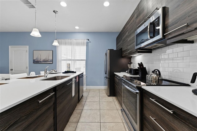 kitchen featuring appliances with stainless steel finishes, hanging light fixtures, light tile patterned floors, sink, and tasteful backsplash