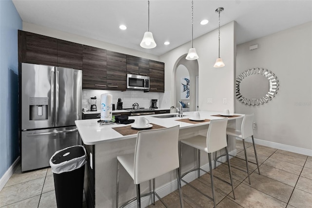 kitchen with appliances with stainless steel finishes, hanging light fixtures, an island with sink, and sink