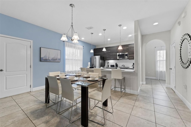 dining area featuring a wealth of natural light, light tile patterned floors, and a chandelier