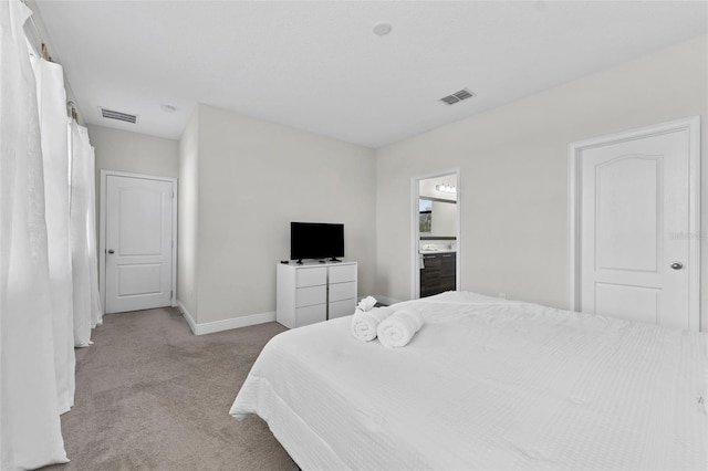 bedroom featuring light colored carpet and ensuite bathroom