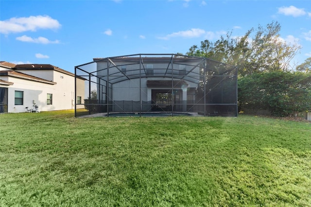 rear view of house with a yard and glass enclosure