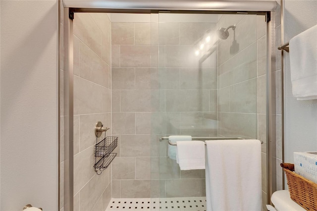 bathroom featuring a shower with shower door and toilet