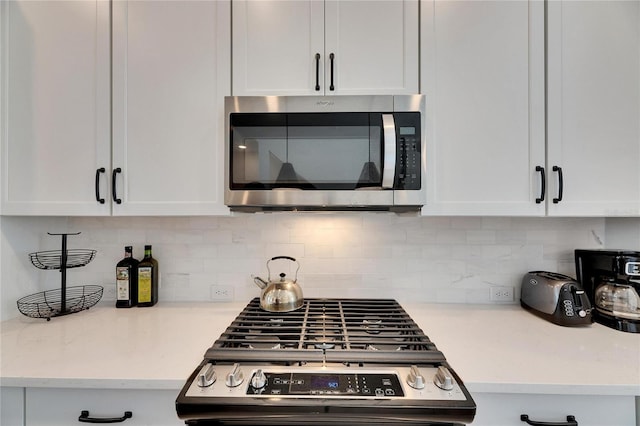 kitchen featuring appliances with stainless steel finishes, white cabinetry, and decorative backsplash