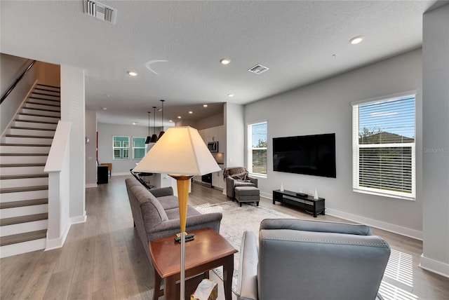 living room featuring a textured ceiling, wood-type flooring, and a wealth of natural light