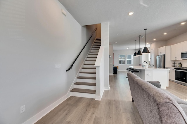 interior space featuring light wood-type flooring, a textured ceiling, and sink