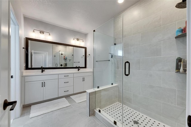 bathroom featuring a textured ceiling, a shower with door, tile patterned flooring, and vanity