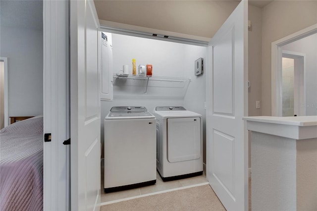 laundry area with washing machine and clothes dryer and light tile patterned floors