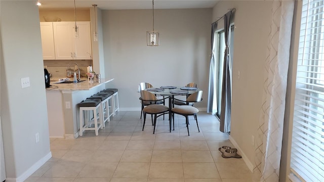 dining space with sink, light tile patterned floors, and a healthy amount of sunlight