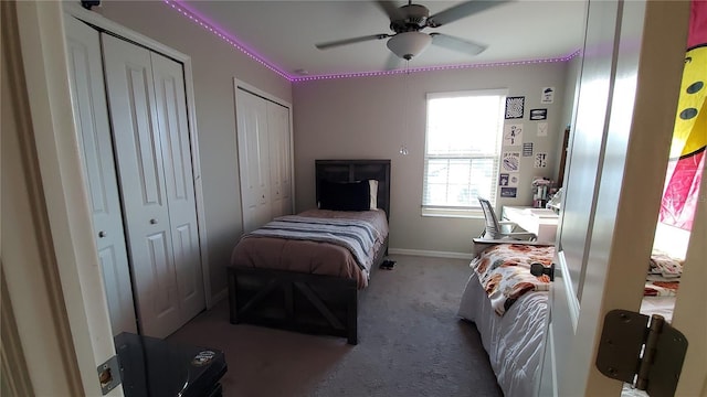 bedroom featuring multiple closets, ceiling fan, and light colored carpet