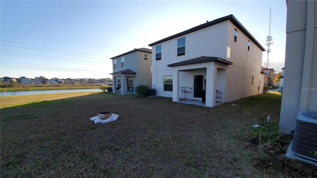 rear view of house with a lawn and central AC