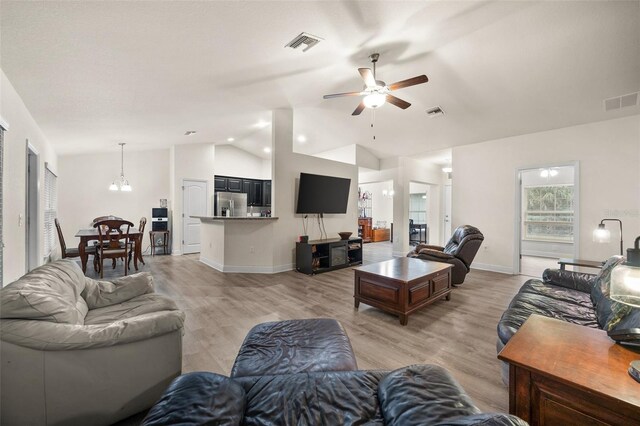 living room featuring light hardwood / wood-style flooring, ceiling fan with notable chandelier, and vaulted ceiling