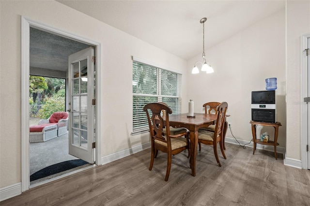 dining space with wood-type flooring, lofted ceiling, and a chandelier