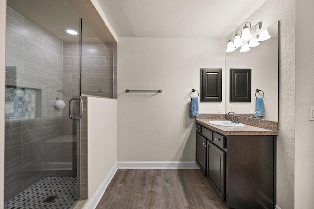 bathroom with vanity, an enclosed shower, hardwood / wood-style floors, and a textured ceiling