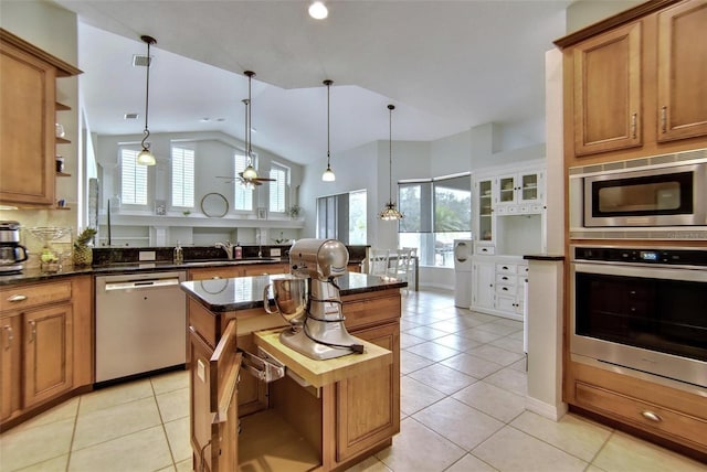 kitchen featuring decorative light fixtures, light tile patterned floors, vaulted ceiling, and stainless steel appliances