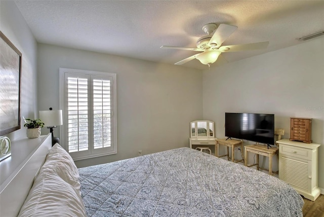 bedroom with ceiling fan, a textured ceiling, and hardwood / wood-style floors