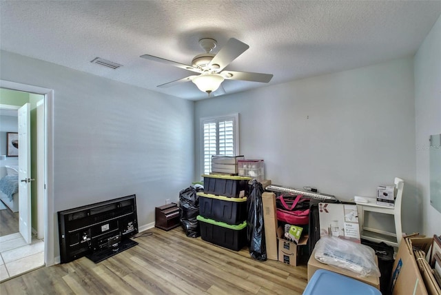 interior space with ceiling fan, a textured ceiling, and light wood-type flooring