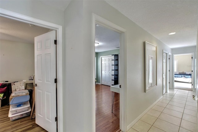 hall featuring light tile patterned flooring and a textured ceiling