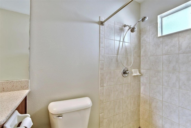 bathroom featuring toilet, a tile shower, and vanity