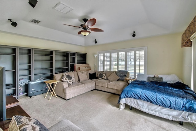 carpeted bedroom with ceiling fan and a raised ceiling