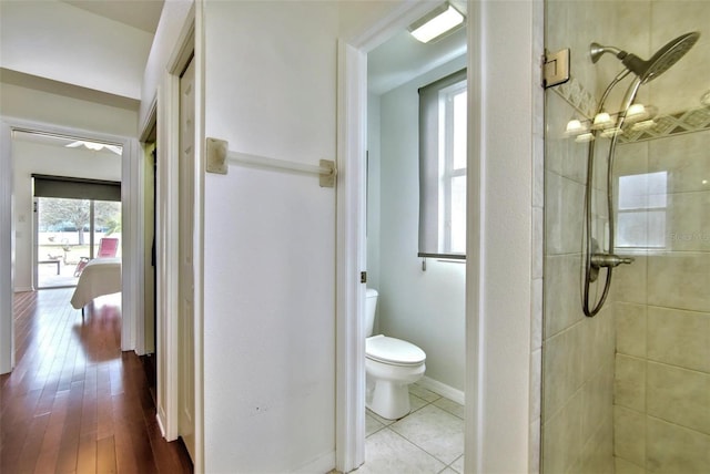 bathroom with toilet, a wealth of natural light, a tile shower, and tile patterned floors