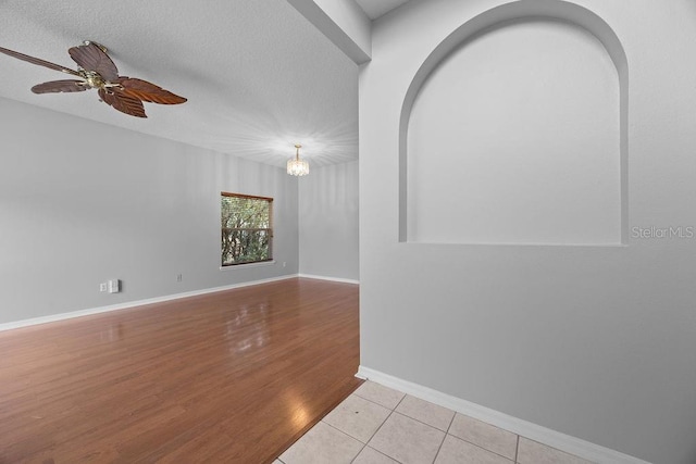 unfurnished living room with a textured ceiling, ceiling fan, and light tile patterned floors