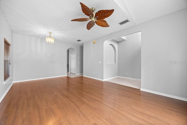 spare room featuring ceiling fan with notable chandelier, a textured ceiling, and light hardwood / wood-style floors