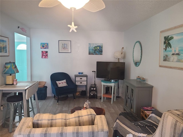 living room with a textured ceiling, ceiling fan, and hardwood / wood-style flooring