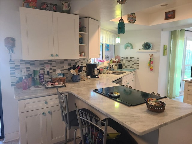 kitchen featuring sink, hanging light fixtures, white cabinetry, and black electric stovetop