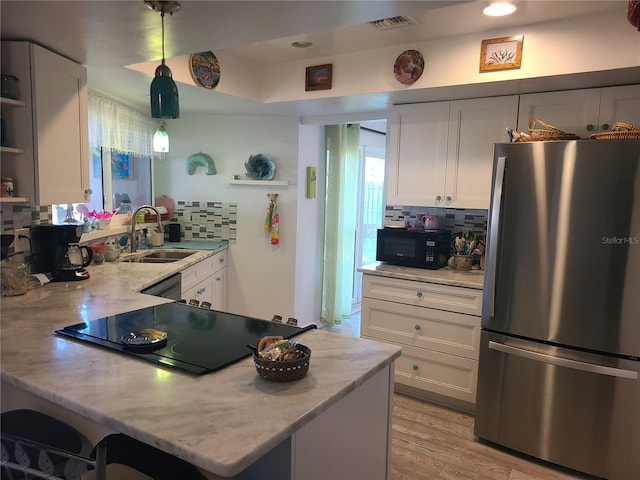 kitchen featuring white cabinets, black appliances, pendant lighting, and sink